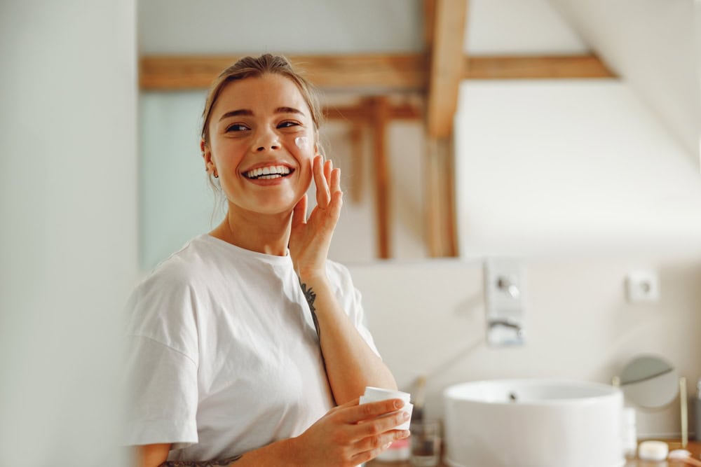 Woman applying moisturizer after microneedling treatment in Cleveland, OH