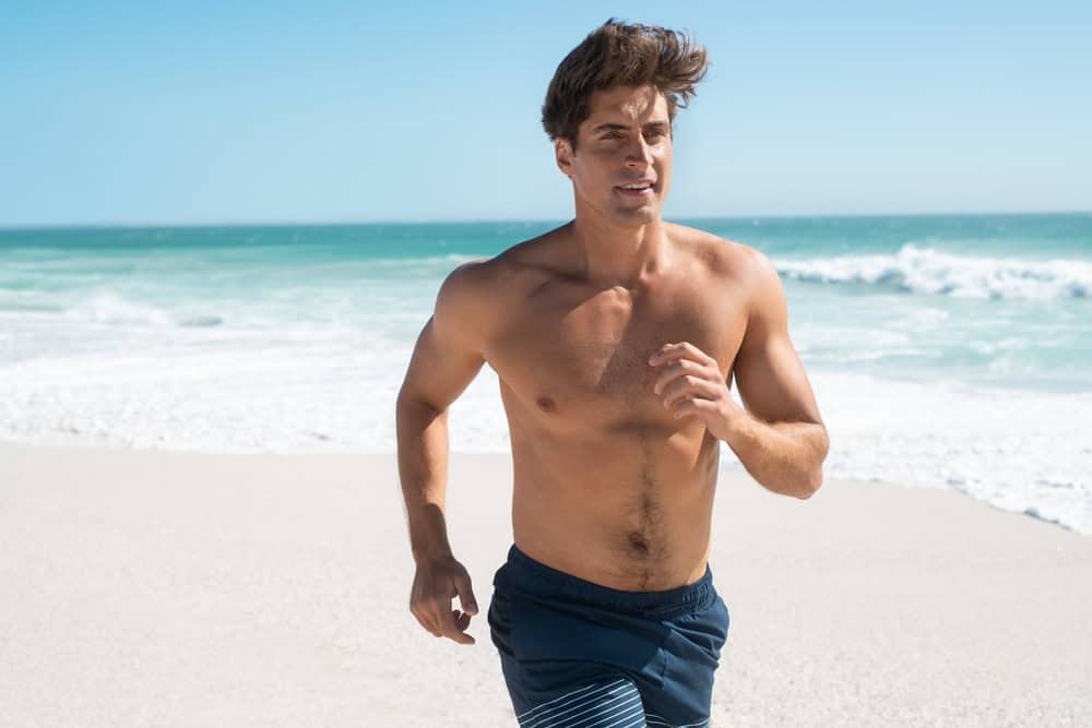 Man running on the beach after dad body contouring procedures